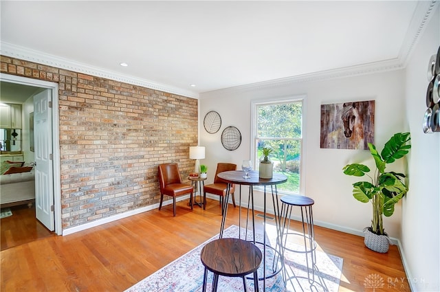 living area featuring light hardwood / wood-style floors, crown molding, and brick wall