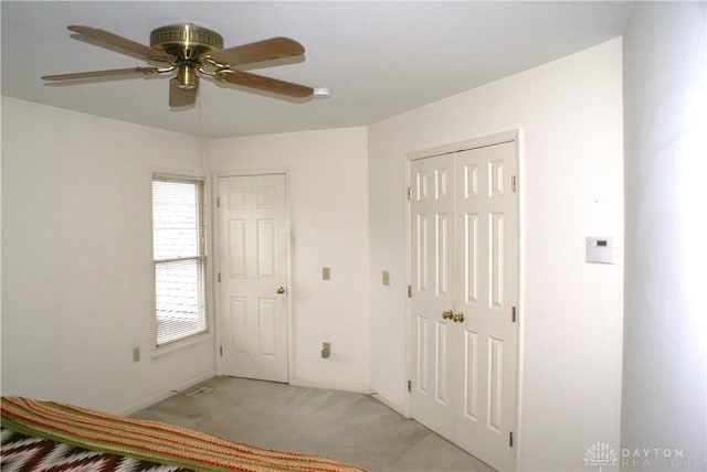 unfurnished bedroom with light carpet, ceiling fan, and a closet