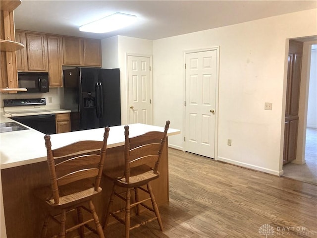 kitchen featuring hardwood / wood-style floors, black appliances, and a breakfast bar