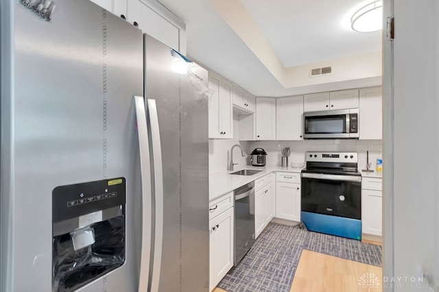 kitchen featuring stainless steel appliances, white cabinets, tasteful backsplash, and sink