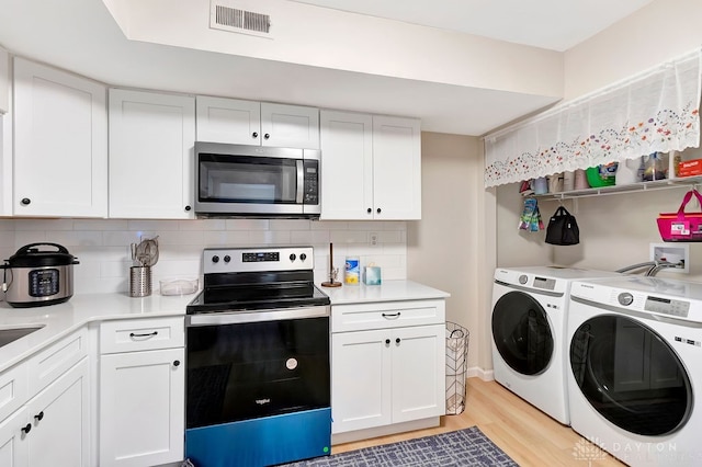 kitchen with stainless steel appliances, light hardwood / wood-style floors, white cabinets, and separate washer and dryer