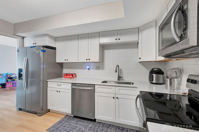 kitchen with stainless steel appliances, light hardwood / wood-style floors, sink, and white cabinetry