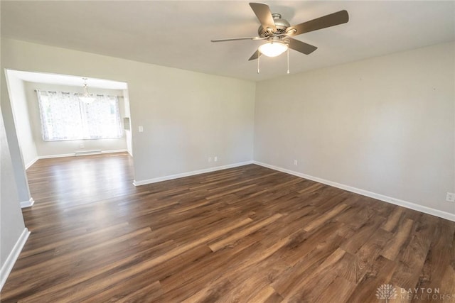 unfurnished room featuring ceiling fan with notable chandelier and dark hardwood / wood-style flooring