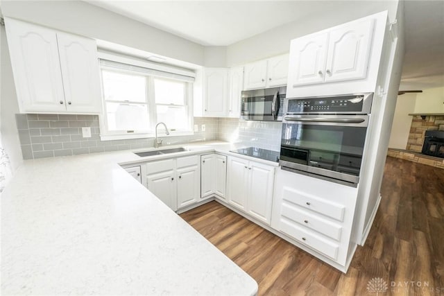 kitchen featuring decorative backsplash, black electric stovetop, dark wood-type flooring, sink, and white cabinets