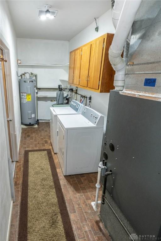 washroom with cabinets, electric water heater, and washing machine and clothes dryer