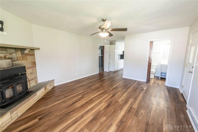 unfurnished living room with a wood stove, ceiling fan, and dark hardwood / wood-style flooring