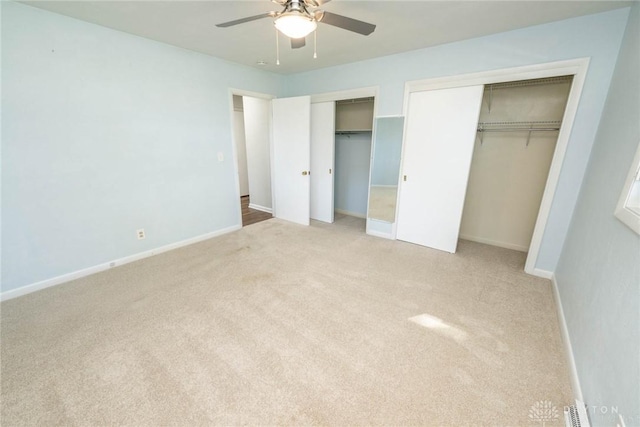 unfurnished bedroom featuring multiple closets, ceiling fan, and light carpet