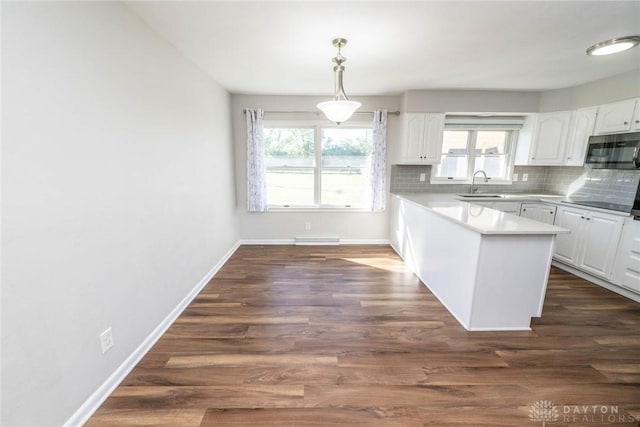 kitchen featuring tasteful backsplash, sink, white cabinets, and pendant lighting