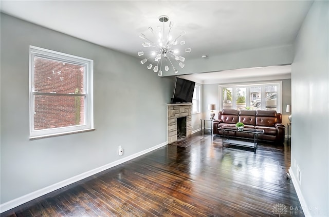 living room with a stone fireplace, an inviting chandelier, and dark hardwood / wood-style floors