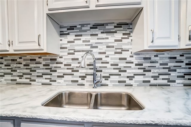 interior details with white cabinetry, sink, and tasteful backsplash