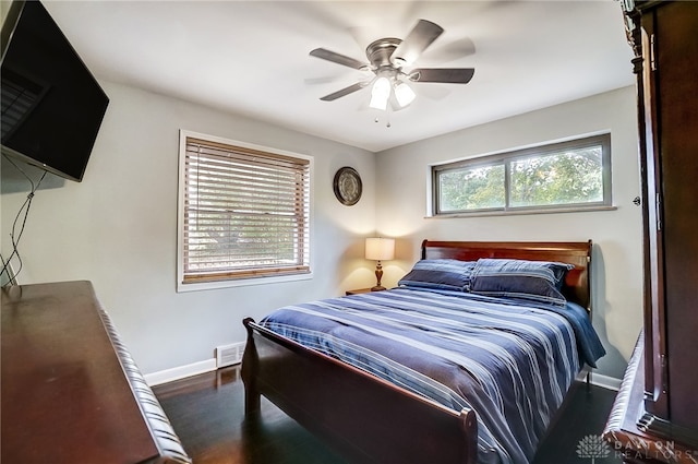 bedroom featuring ceiling fan, dark hardwood / wood-style floors, and multiple windows