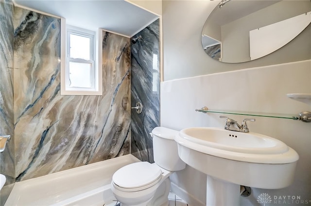 bathroom featuring tile patterned flooring, a tile shower, sink, and toilet