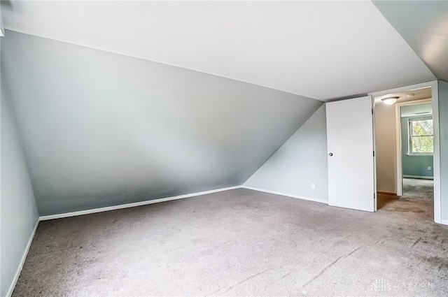 bonus room with vaulted ceiling and carpet