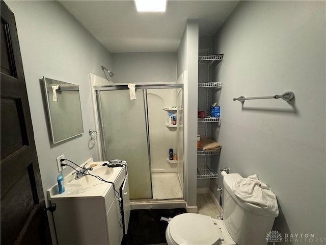 bathroom with a shower with door, vanity, and toilet