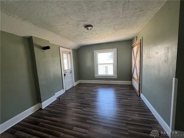 spare room with dark hardwood / wood-style flooring, lofted ceiling, and a textured ceiling