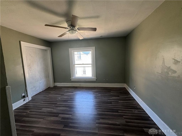 unfurnished room featuring dark wood-type flooring and ceiling fan