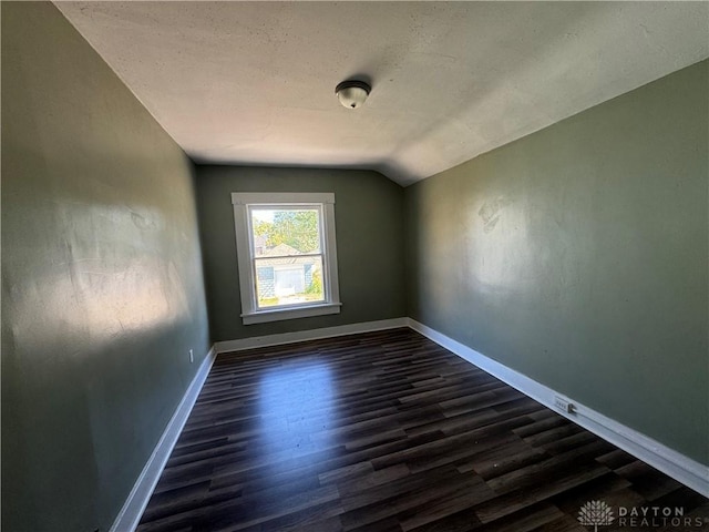 additional living space featuring dark wood-type flooring and vaulted ceiling