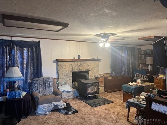 living room featuring carpet floors, ceiling fan, and a wood stove