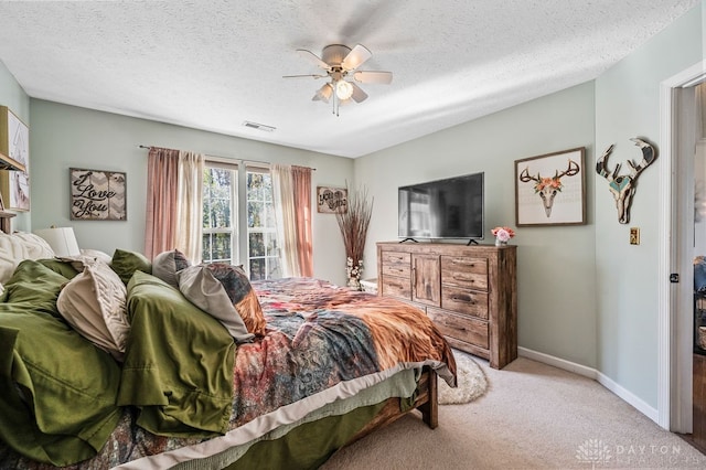 bedroom featuring ceiling fan, a textured ceiling, and light carpet