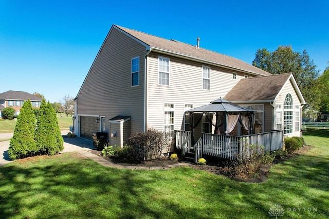 rear view of house featuring a garage, a yard, a gazebo, and a deck