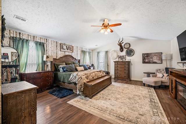 bedroom featuring lofted ceiling, dark wood-type flooring, a textured ceiling, and ceiling fan