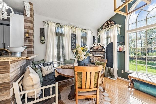 dining room with plenty of natural light, vaulted ceiling, a chandelier, and light hardwood / wood-style flooring