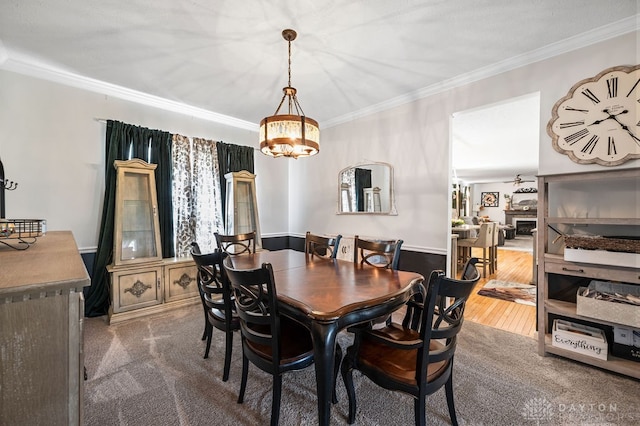 dining room featuring an inviting chandelier, hardwood / wood-style flooring, a fireplace, and ornamental molding