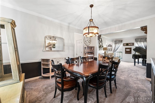 carpeted dining area featuring ornamental molding and an inviting chandelier