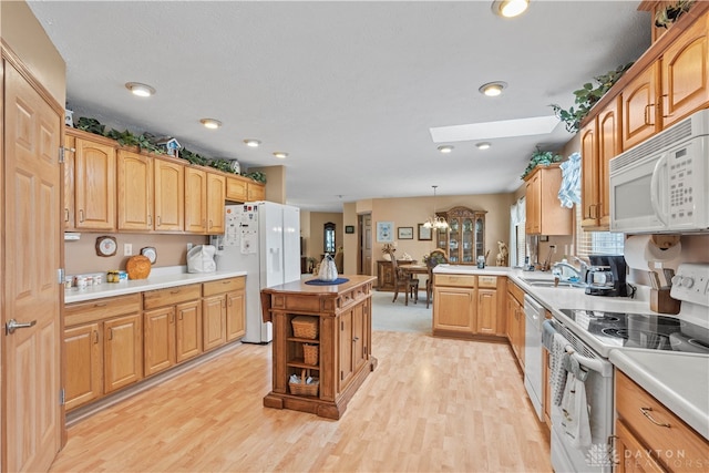 kitchen featuring a skylight, white appliances, a chandelier, and light hardwood / wood-style flooring