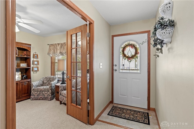 foyer entrance featuring ceiling fan and light carpet