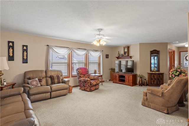 carpeted living room with ceiling fan and a textured ceiling