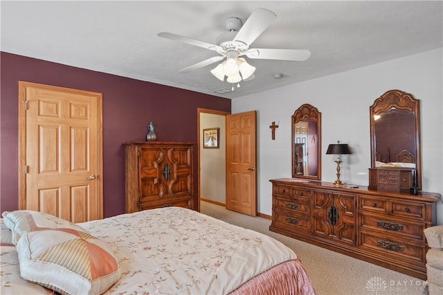 bedroom featuring light carpet, a textured ceiling, and ceiling fan