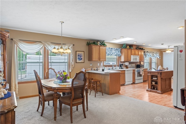 dining room featuring ceiling fan with notable chandelier, light hardwood / wood-style floors, sink, and a wealth of natural light