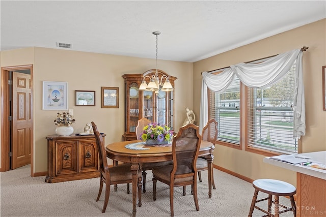 carpeted dining room featuring a chandelier