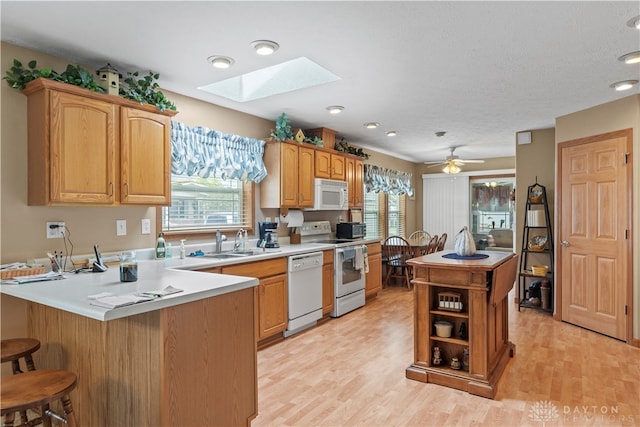 kitchen featuring ceiling fan, white appliances, sink, kitchen peninsula, and light hardwood / wood-style flooring