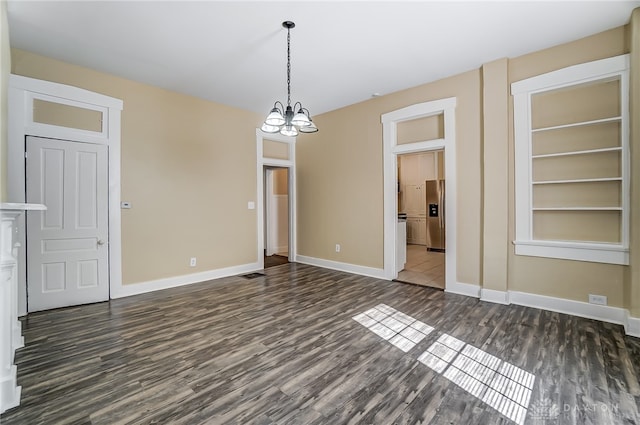 unfurnished dining area with built in shelves, a notable chandelier, and dark hardwood / wood-style flooring