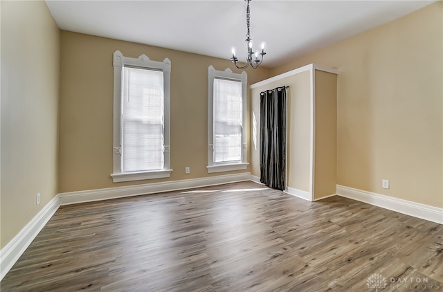 spare room with hardwood / wood-style floors and a notable chandelier