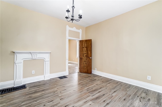 unfurnished living room with light hardwood / wood-style floors and a chandelier