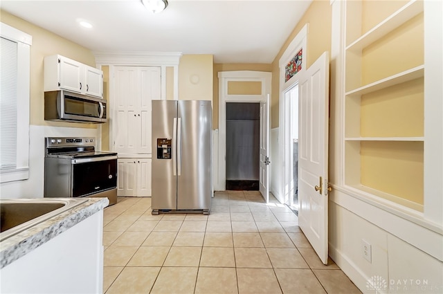 kitchen with stainless steel appliances, light tile patterned floors, and white cabinetry