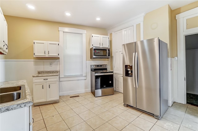 kitchen with appliances with stainless steel finishes, sink, light tile patterned flooring, and white cabinets