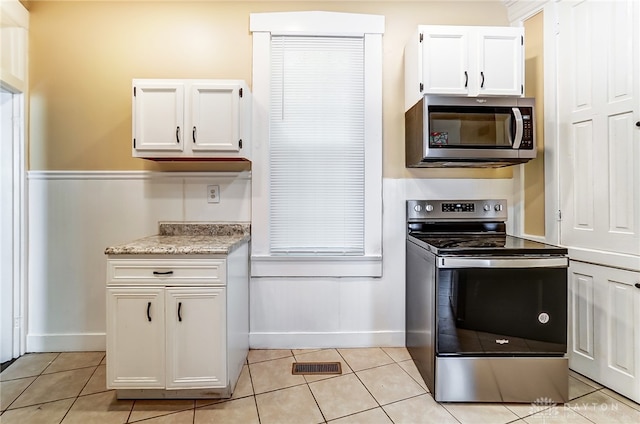 kitchen with appliances with stainless steel finishes, white cabinetry, and light tile patterned floors