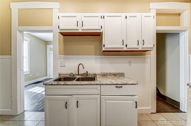 kitchen featuring light tile patterned flooring, light stone countertops, sink, and white cabinetry