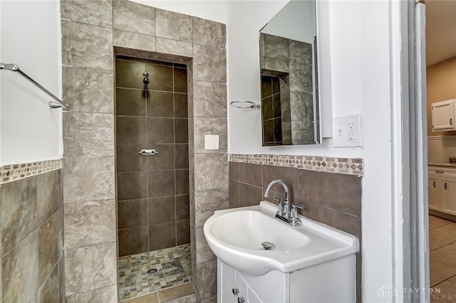 bathroom featuring a tile shower, vanity, and tile walls