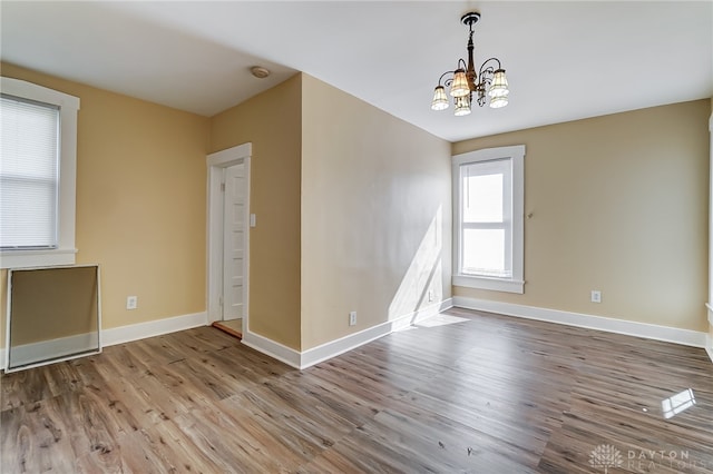 unfurnished room featuring hardwood / wood-style flooring and a chandelier