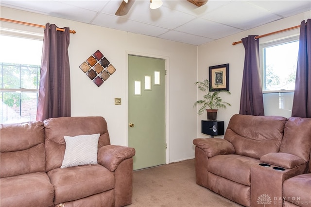 living room featuring a drop ceiling, ceiling fan, and light colored carpet