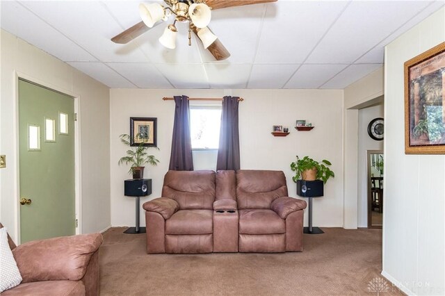 living room with a drop ceiling, ceiling fan, and carpet