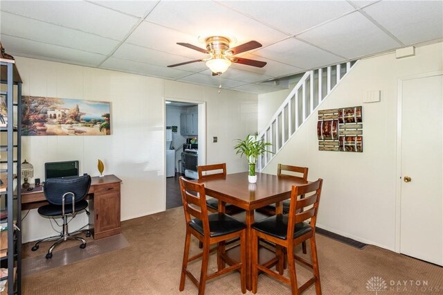 carpeted dining area featuring ceiling fan and a paneled ceiling