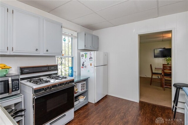 kitchen featuring a drop ceiling, white appliances, and dark hardwood / wood-style flooring