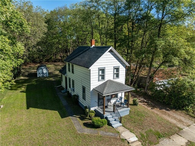 view of front of property with a front yard, a storage unit, and covered porch