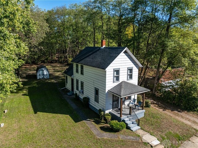 view of front of home with a shed, a front lawn, and covered porch